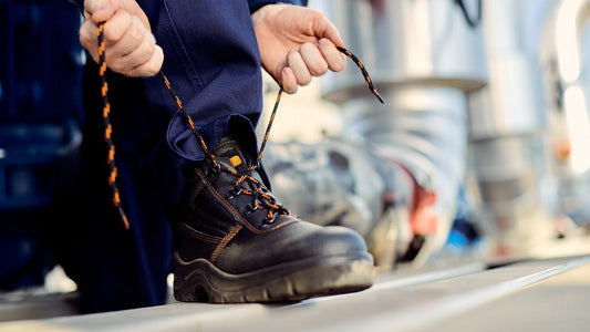 A man tying the laces of black work boots